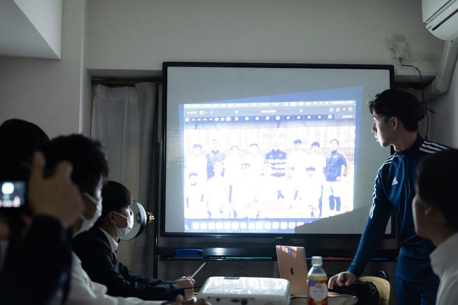 スポーツセミナーで、参加者にスクリーンを使って説明する講師
